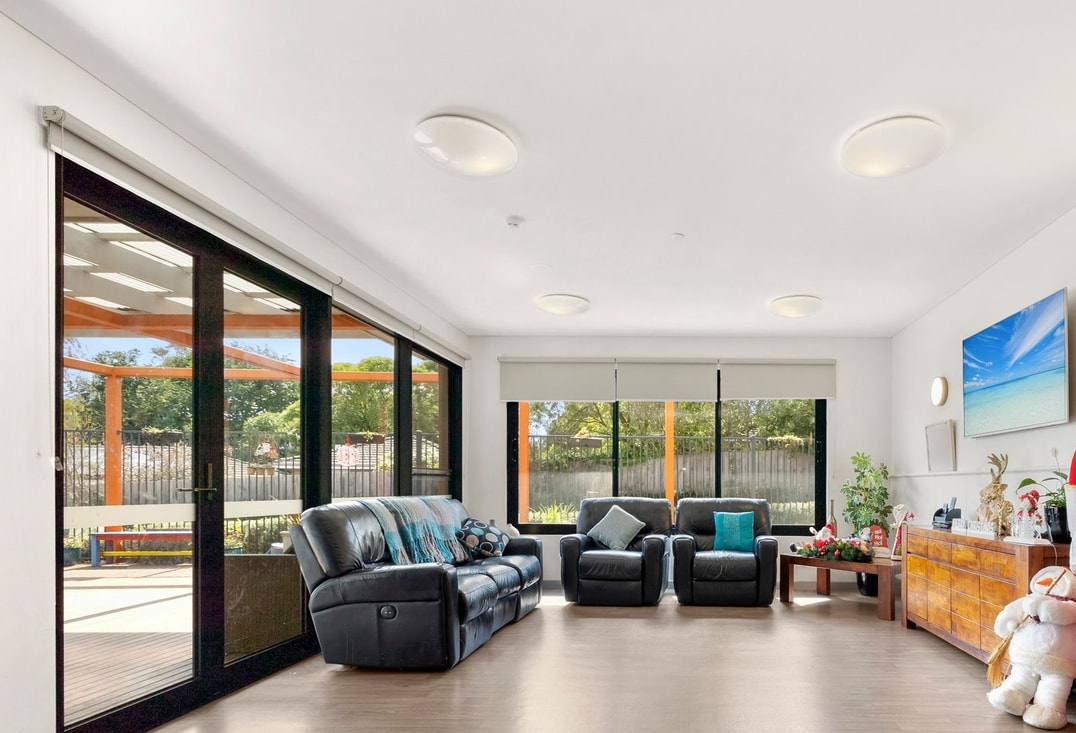 Living area with black recliners and large TV