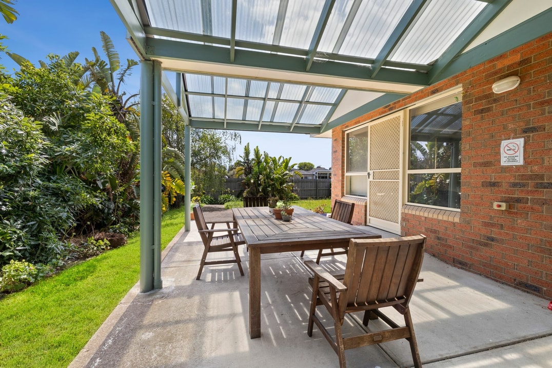 Backyard undercover area with table and chairs next to garden