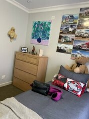 Andrews room in SIL housing, a neat bed, dresser and posters on the wall