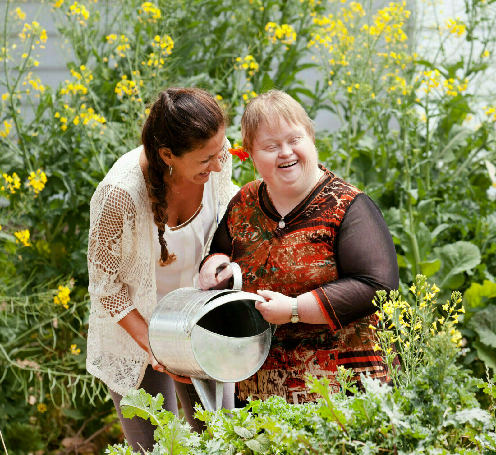 A woman is helping a girl watering the garden