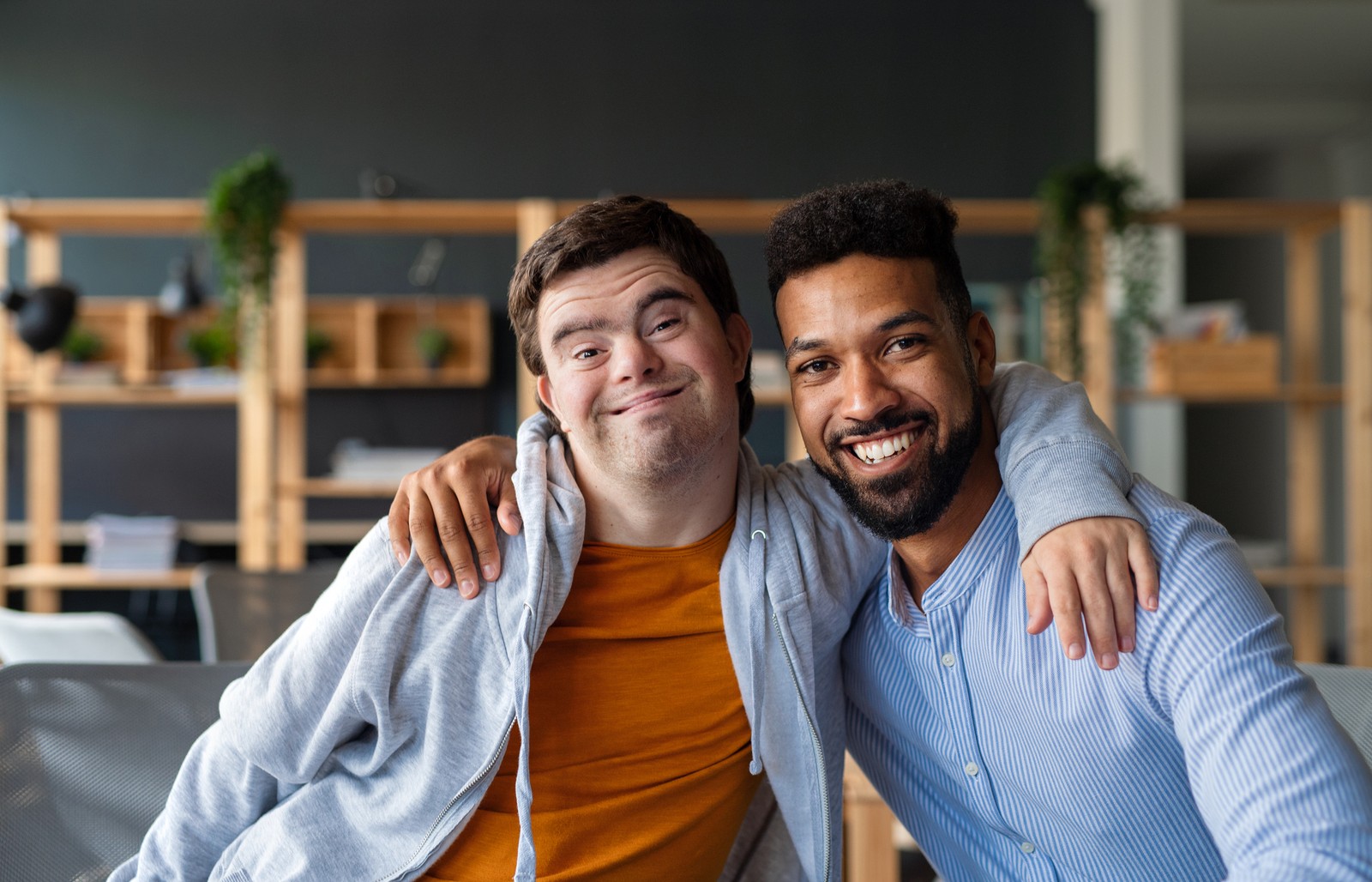 Man with disability and another man hugging and smiling.