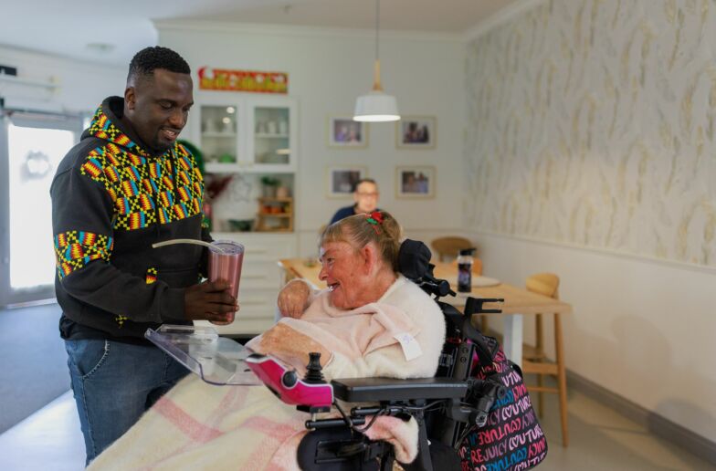 A man handing a bottle of water to a woman on a wheelchair