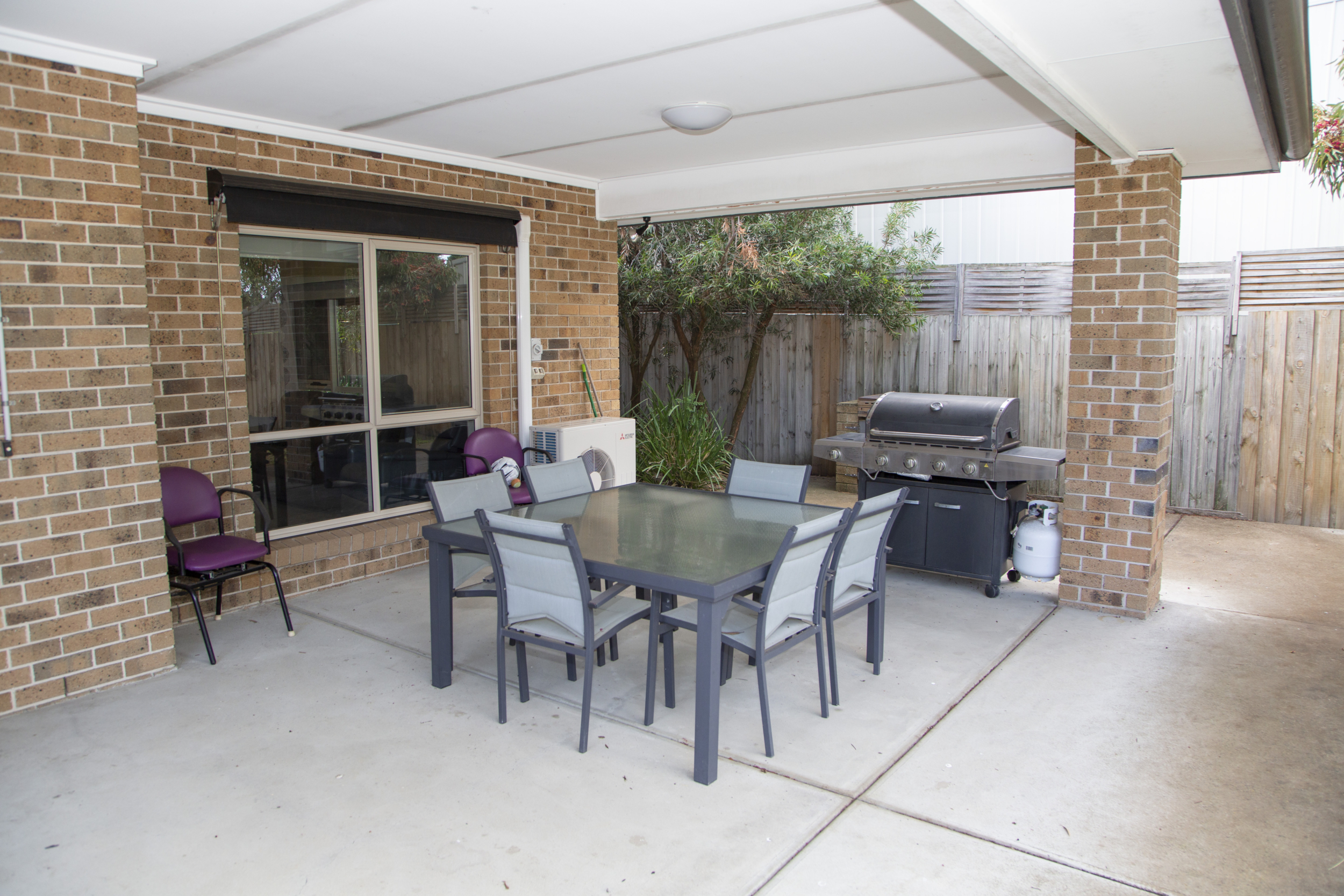 Backyard area with table and chairs and barbeque undercover