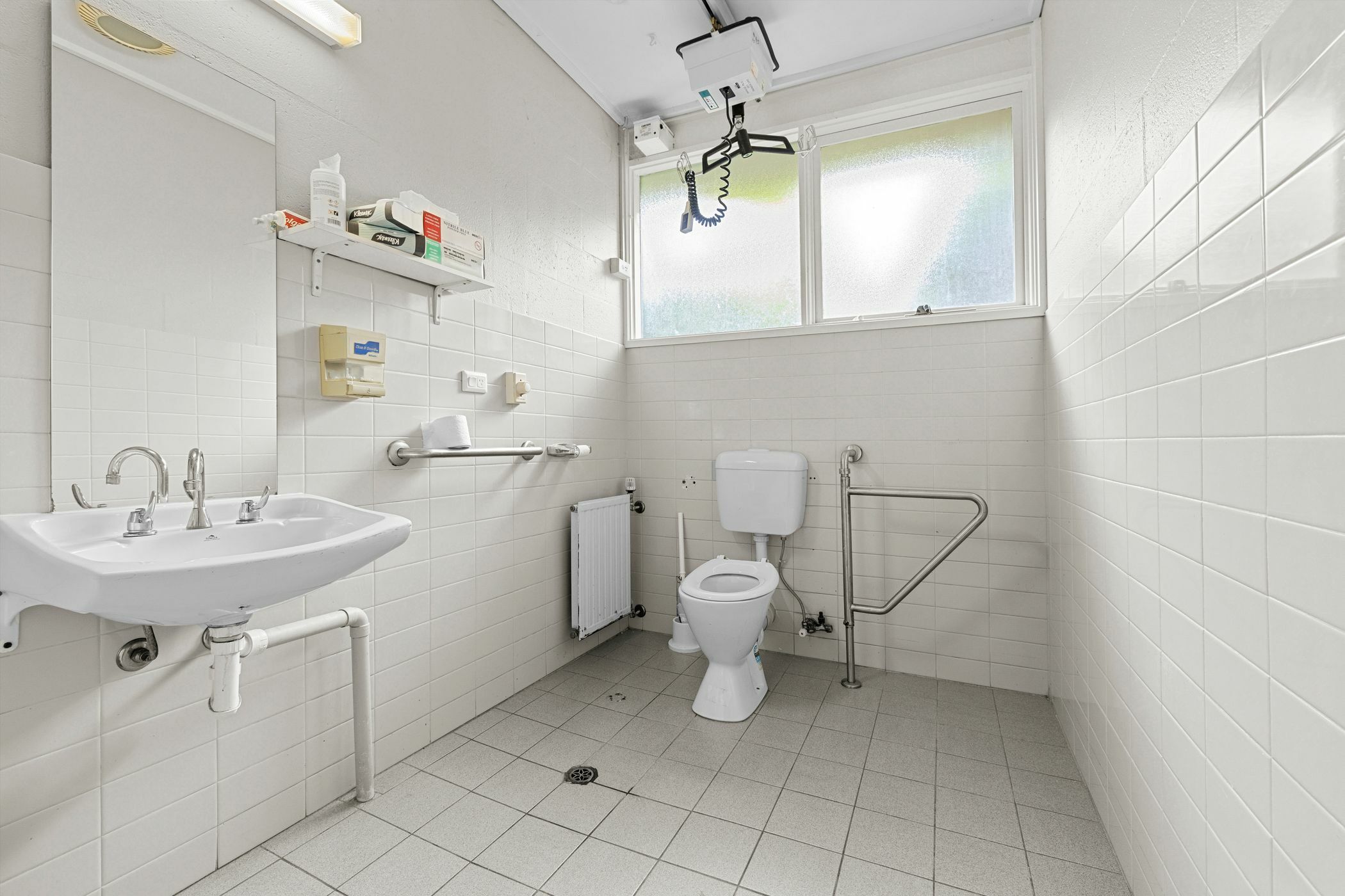 Accessible bathroom with ceiling hoist grab rails and white subway tiles