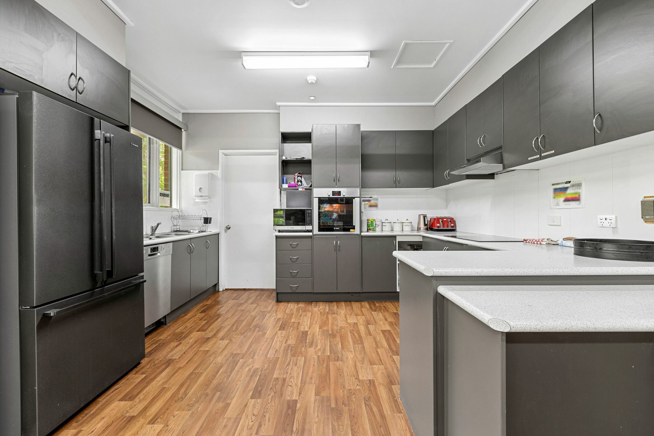 Modern and large kitchen with grey cabinetry and timber floors