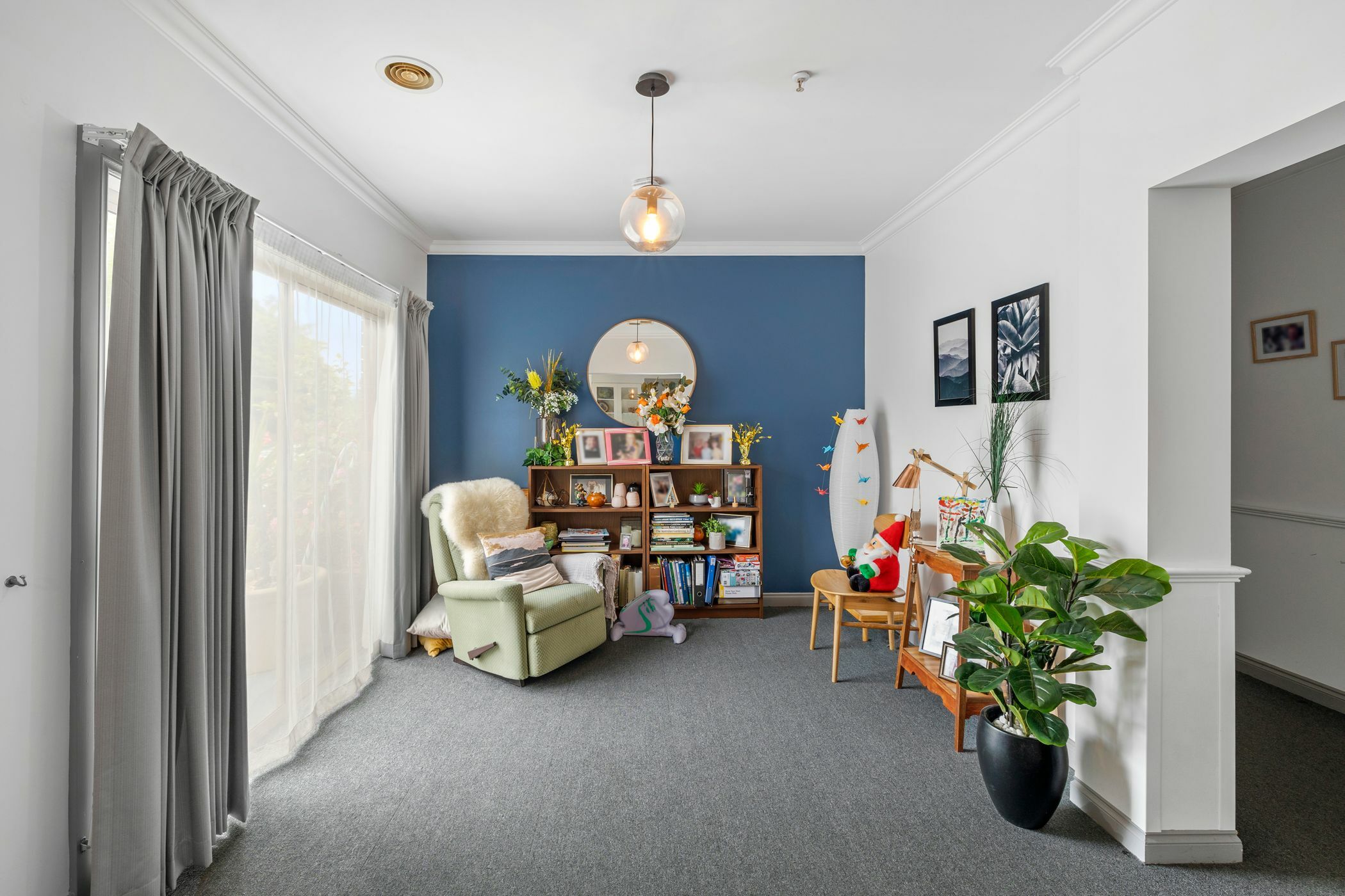 Stylish sitting room with a blue feature wall recliner chair potted plant and bookshelf