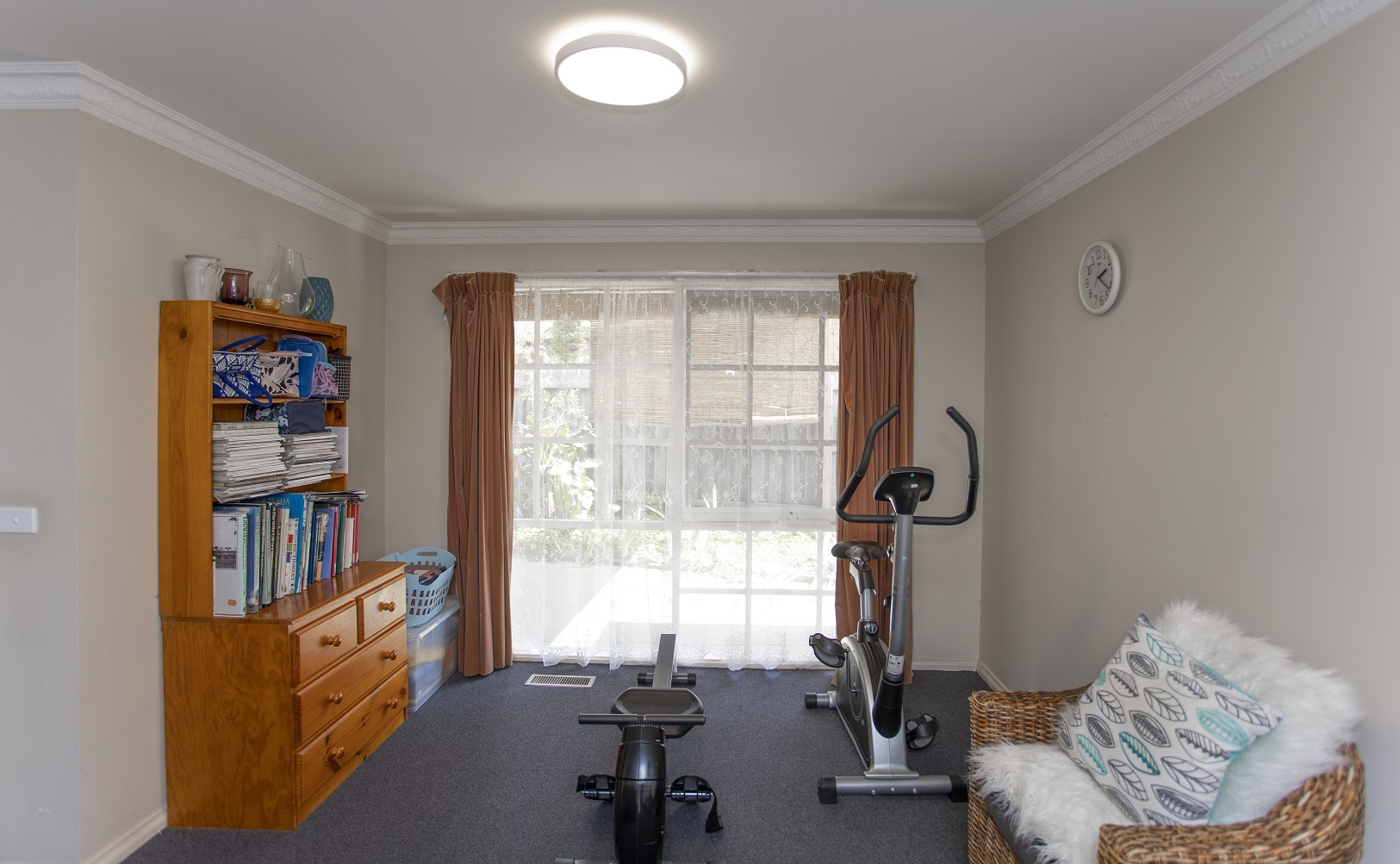 Living space that has an exercise bike and a bookshelf and large window