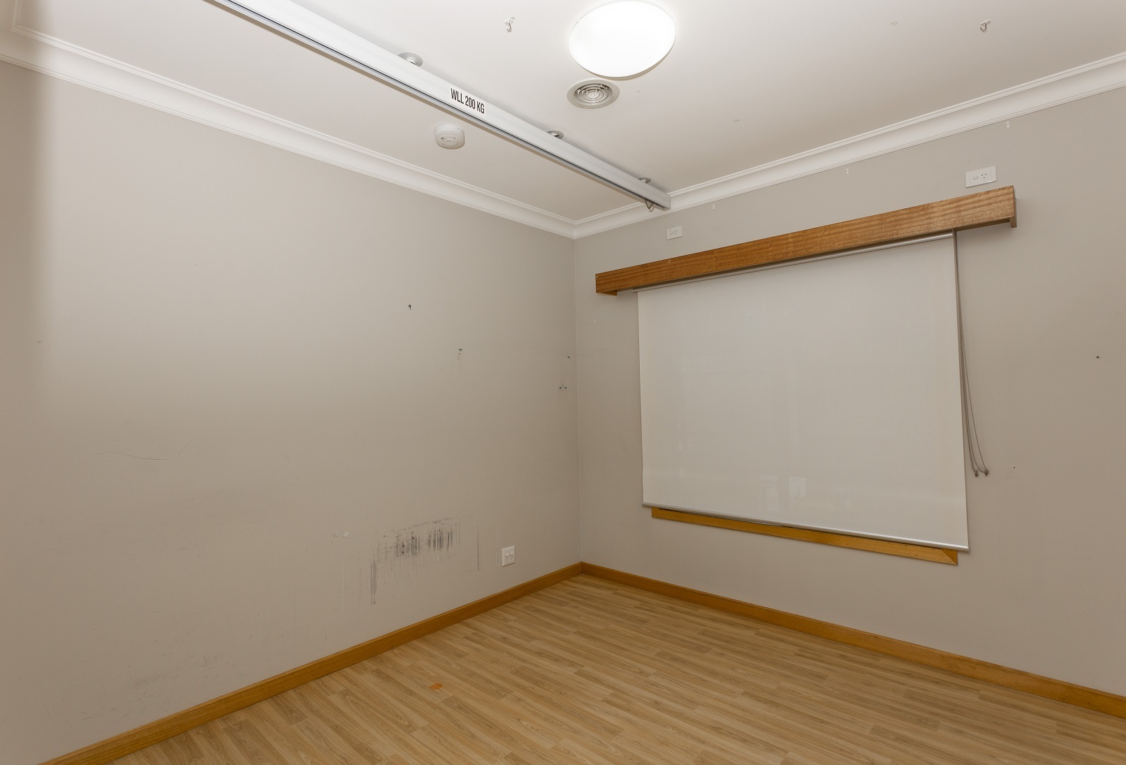 Bedroom with ceiling track and wooden floorboards