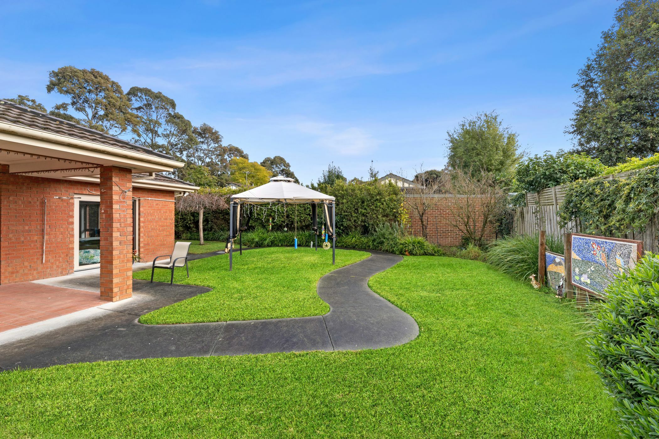 Backyard lawn with artwork near fenceline