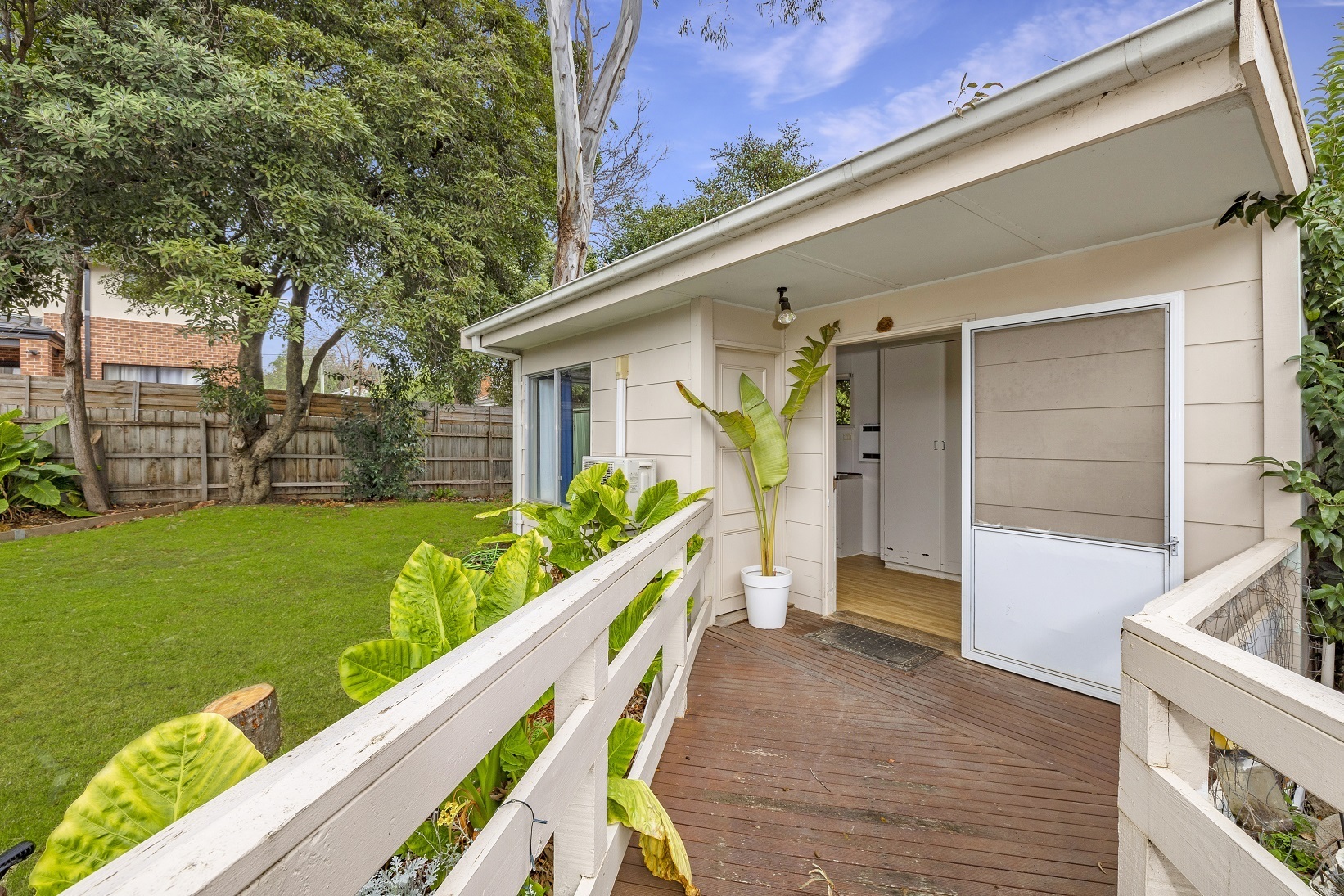 Wooden walkway to front door of bungalow in backyard of house