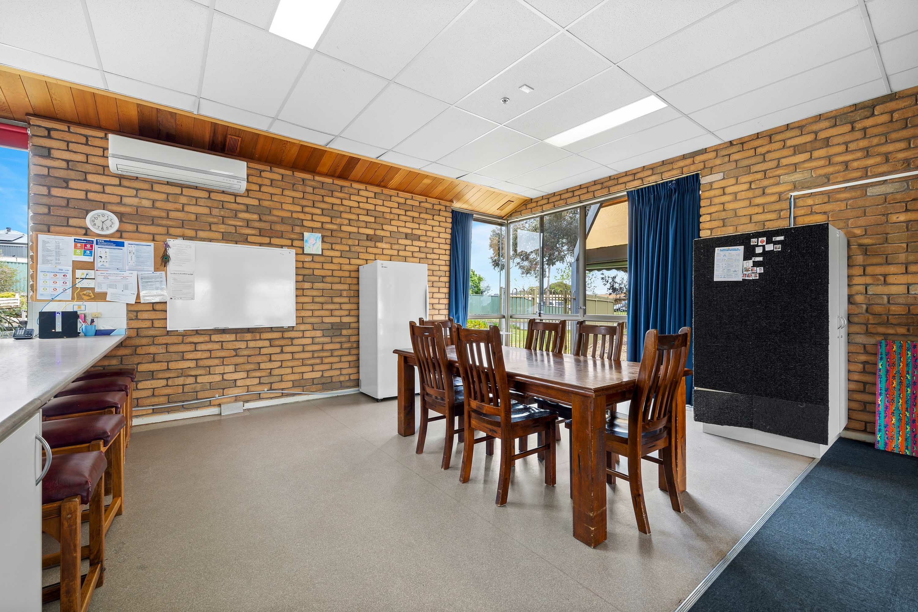 Dining area with brick wall and large black fridge